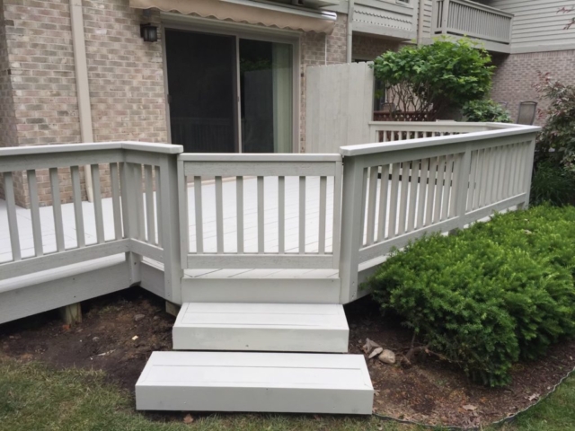 a light gray colored back deck with steps and gate