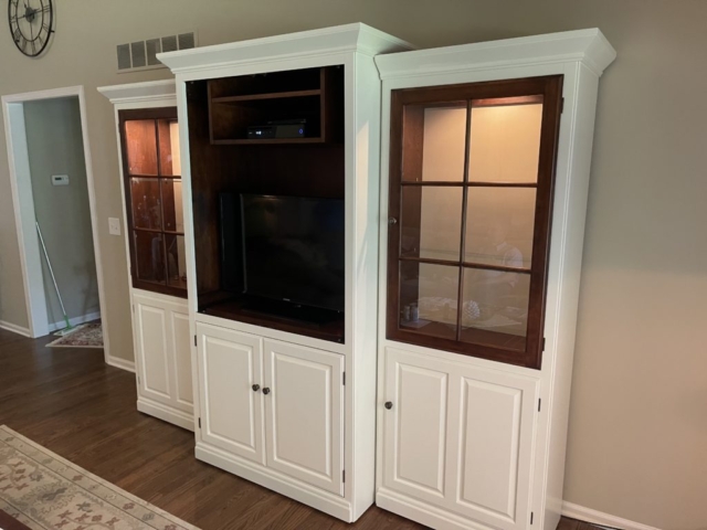 an entertainment center painted white with cherry wood around windows